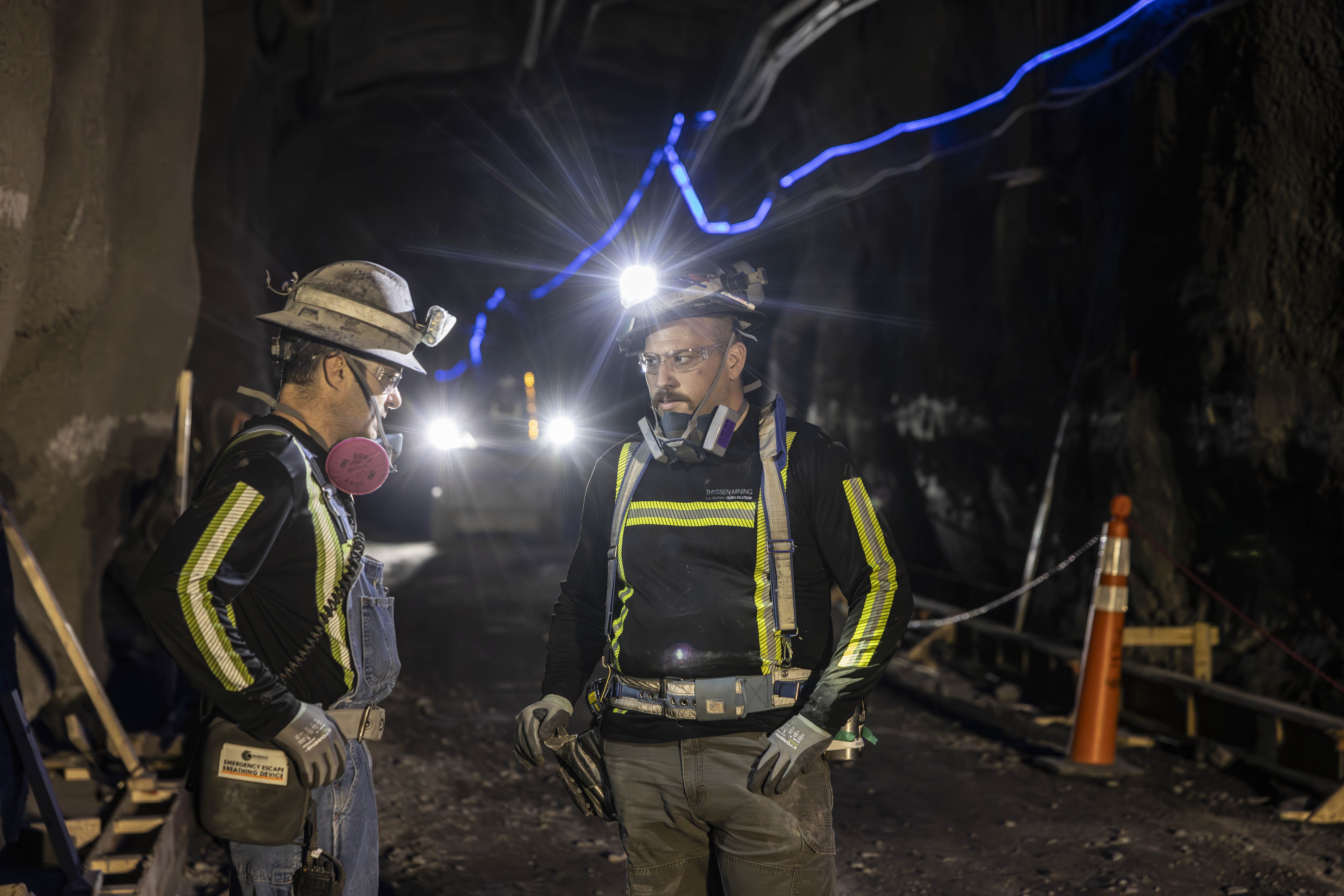 Two underground mine workers in protective equipment during an active shift