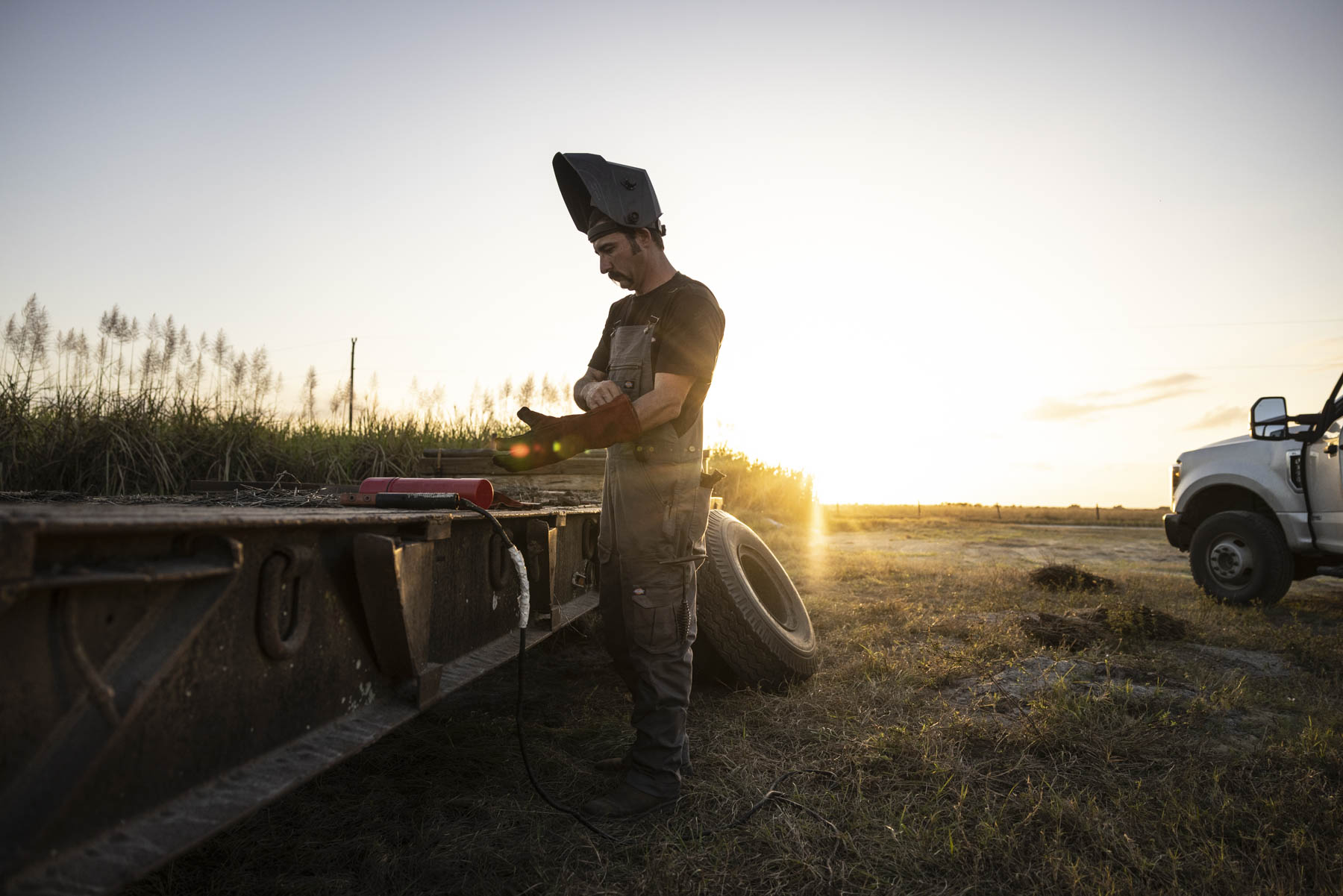 Field welder preparing equipment at sunset on an active industrial site