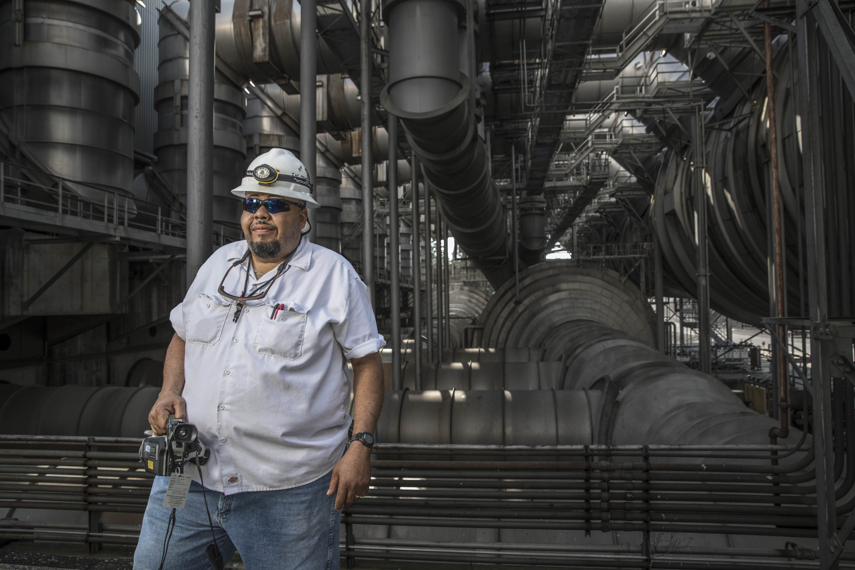 Industrial specialist photographed among large-scale process equipment