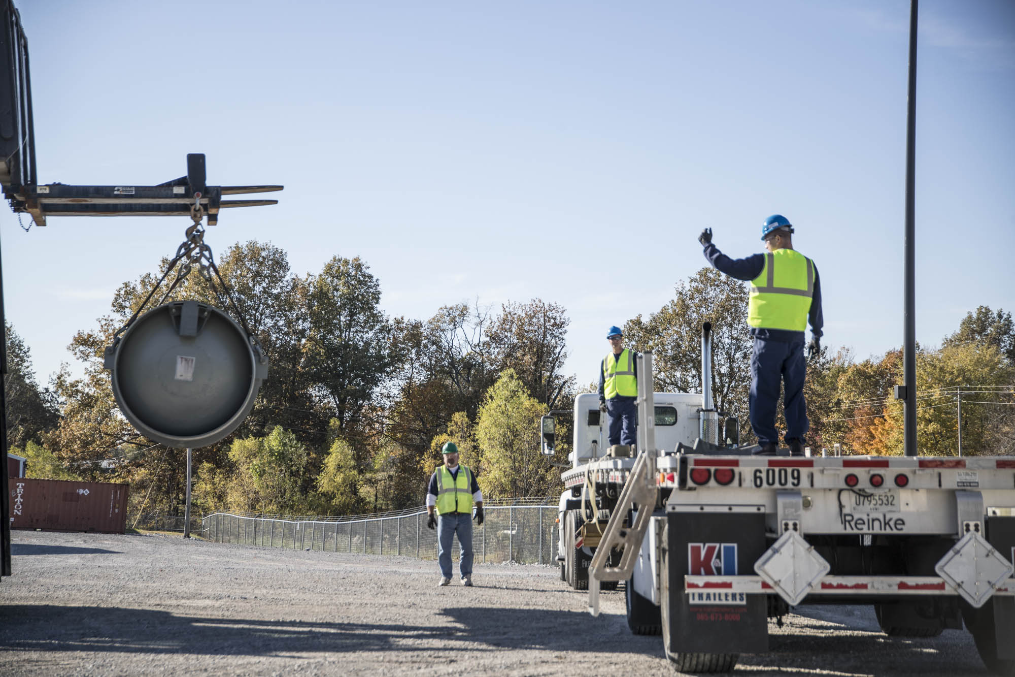 Crew guiding a cask onto a flatbed trailer during outdoor loadout