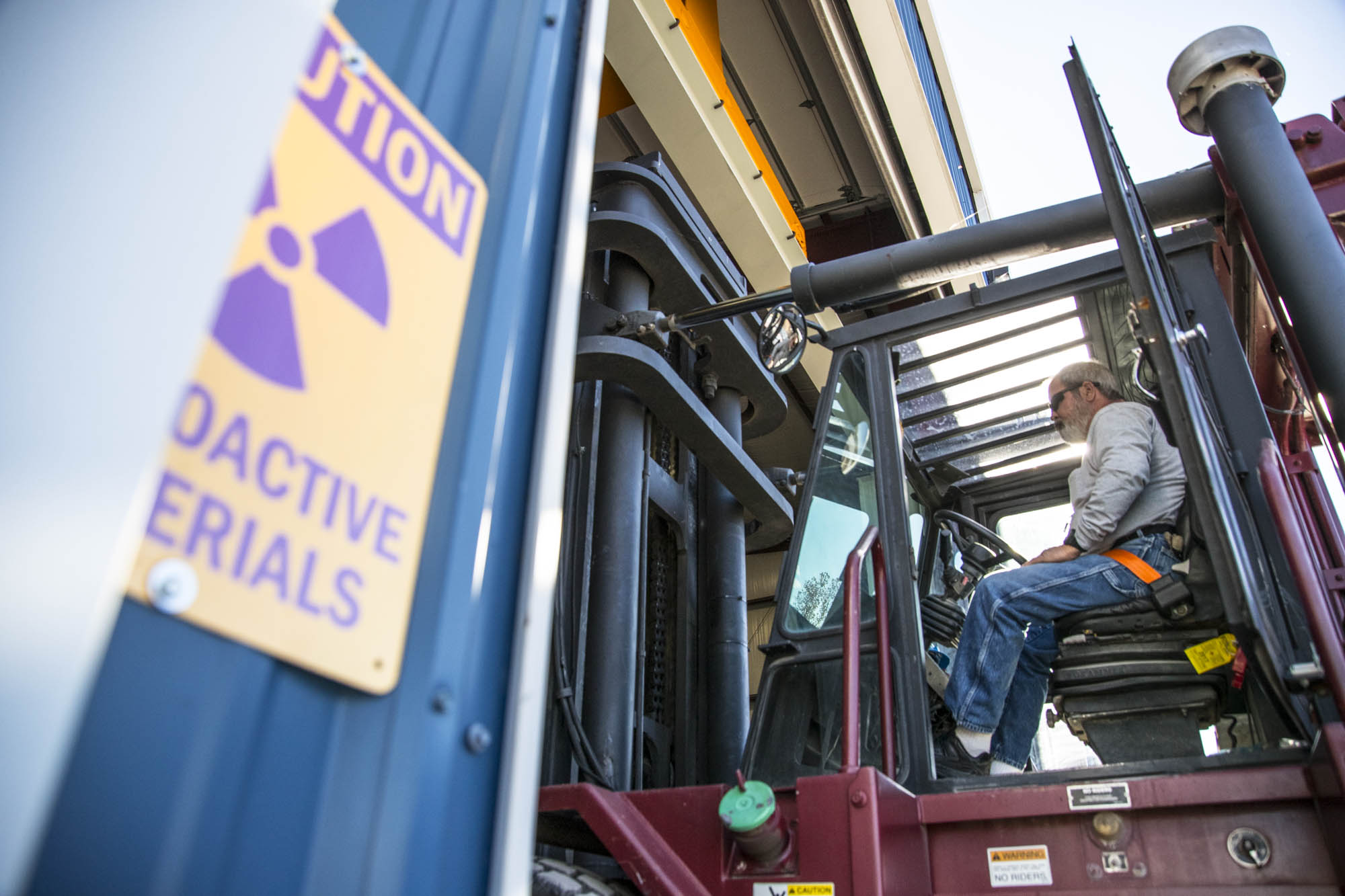 Forklift operator staged beside a radioactive materials caution sign