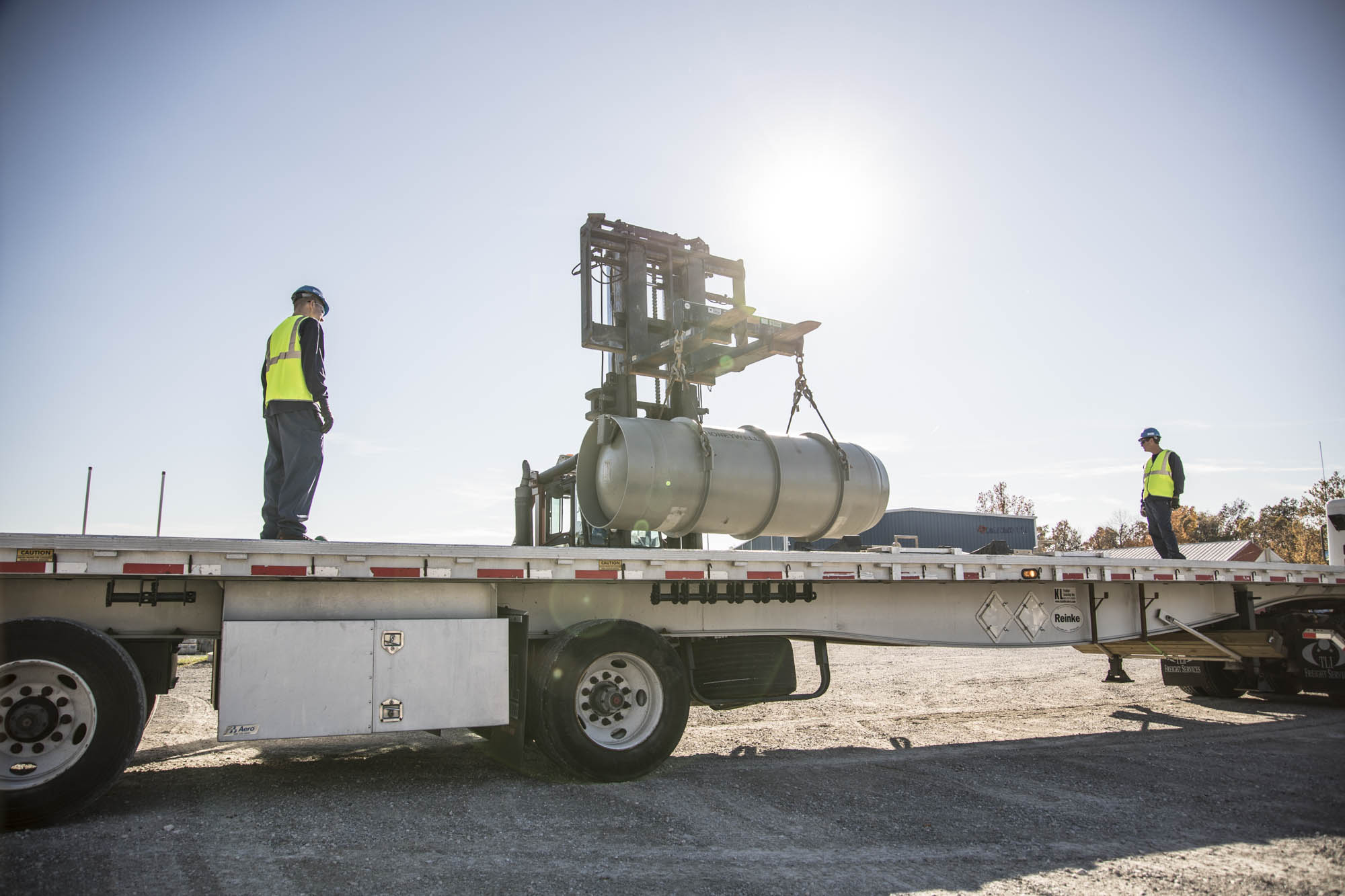 Crew positioning a cask on a flatbed trailer bed for transport