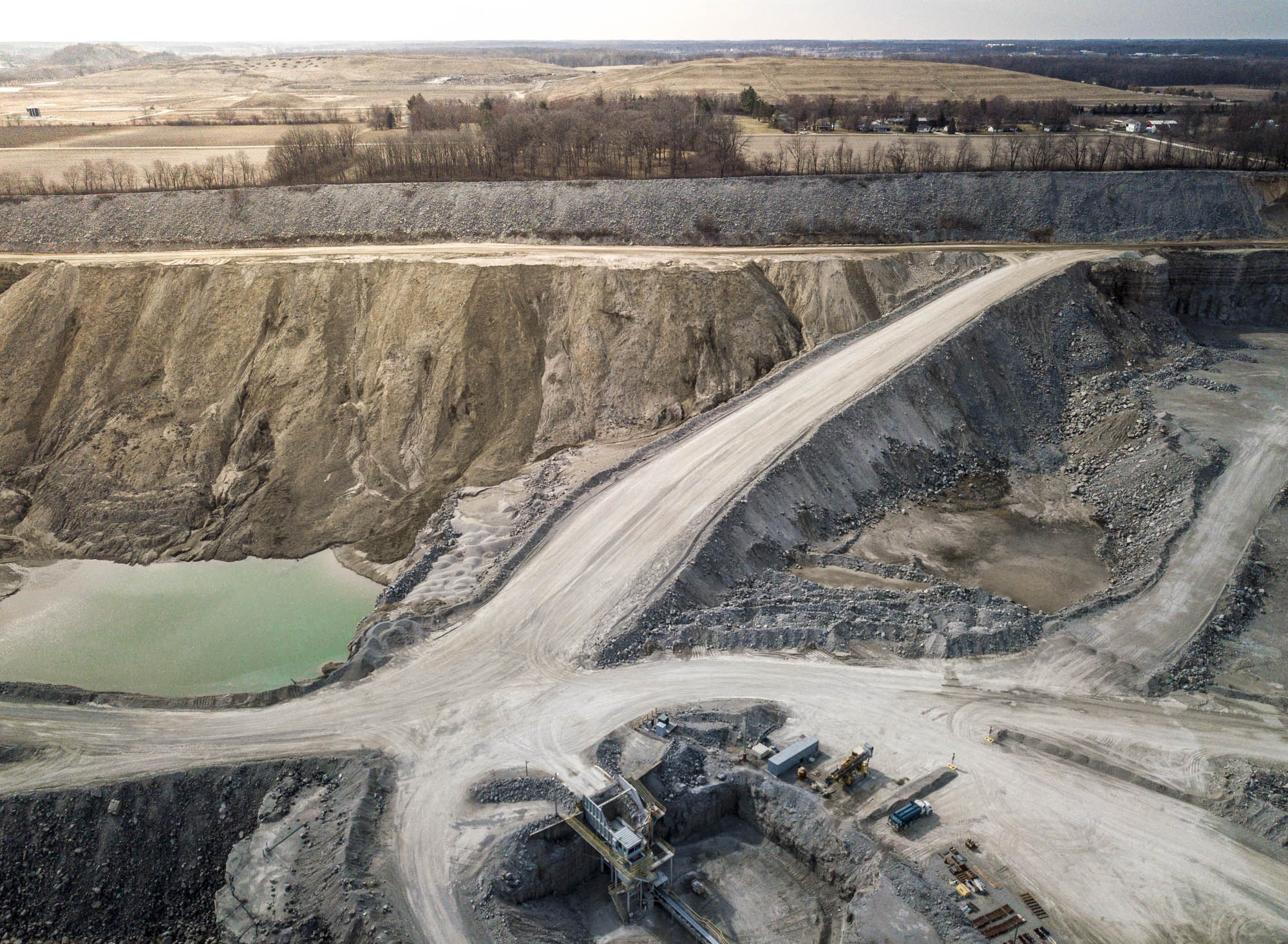Aerial view of a haul road descending past a quarry settling pond