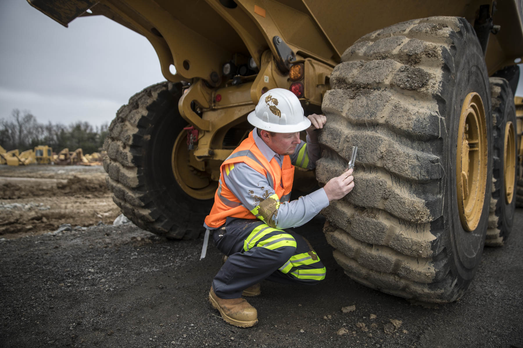 Industrial technician inspecting a loader tire during heavy-equipment maintenance