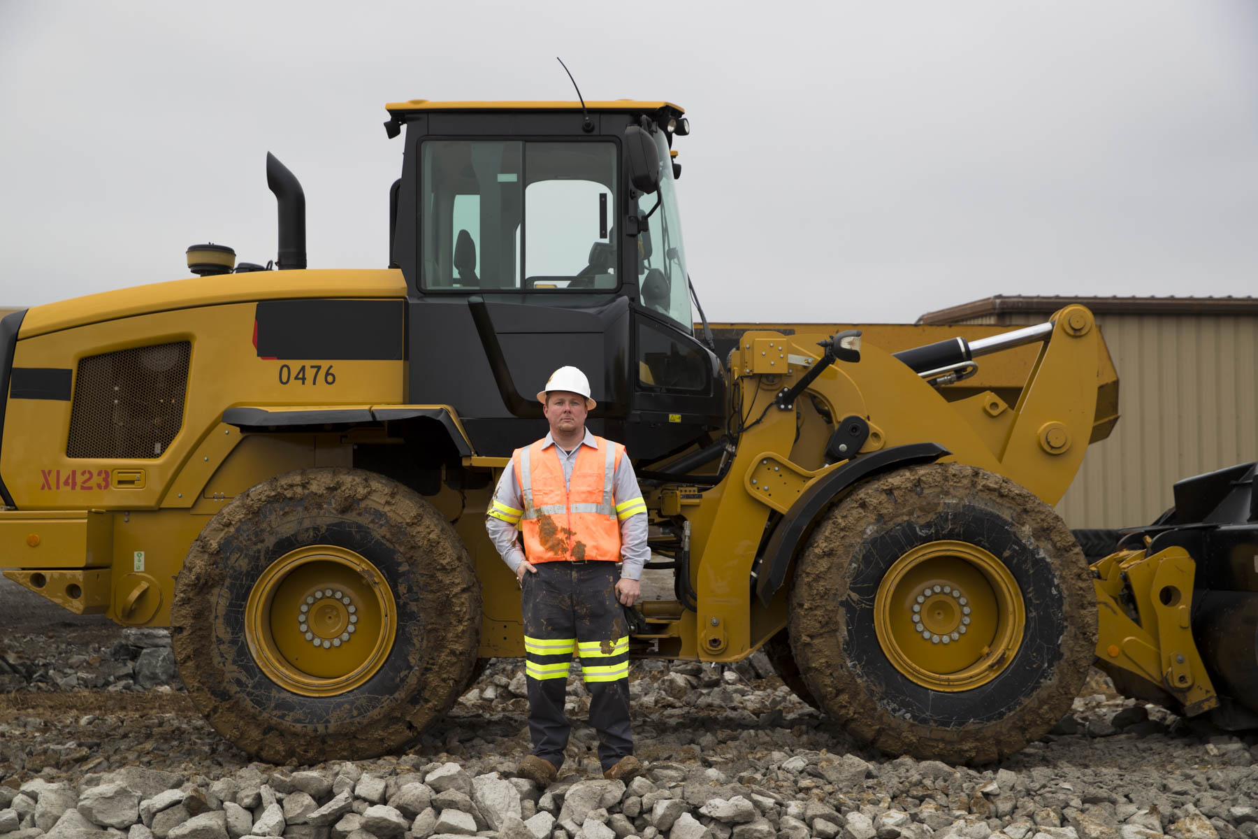 Heavy-equipment operator standing beside a wheel loader on an industrial work site