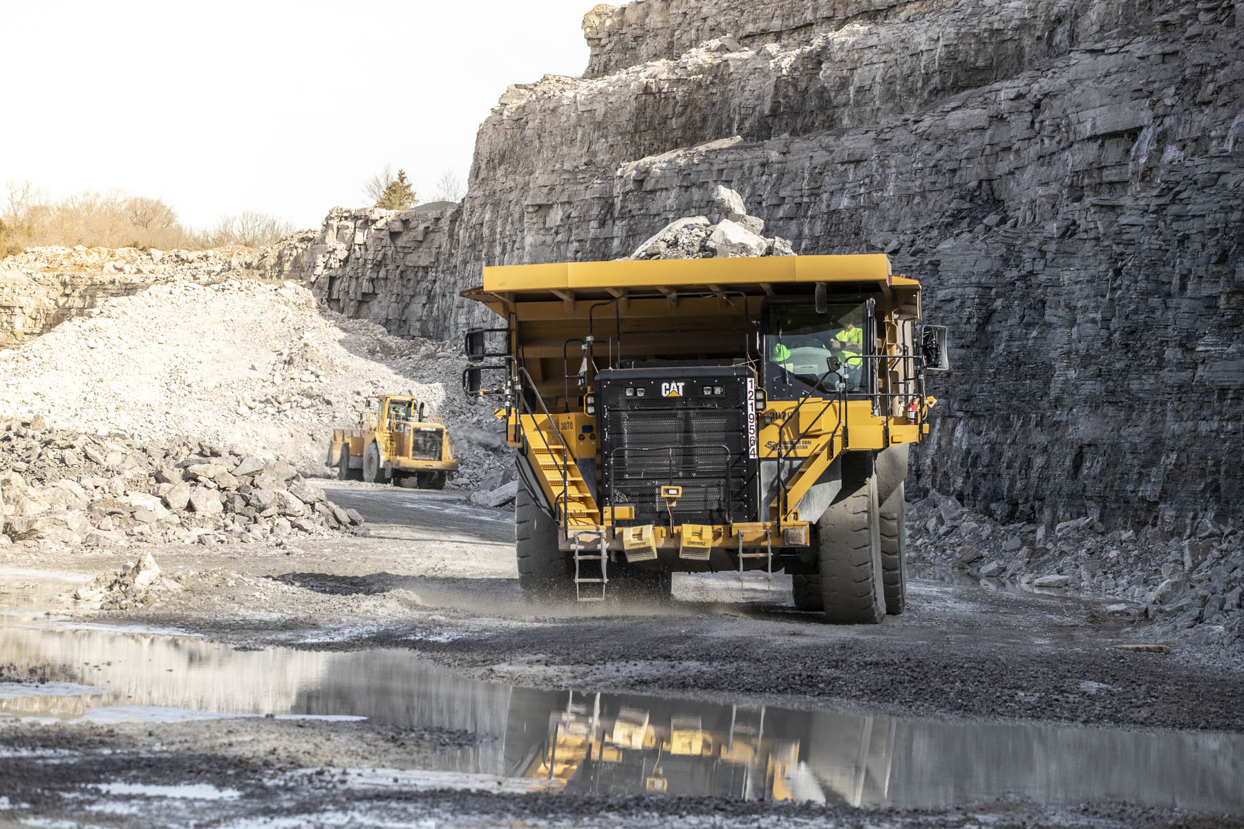 Mining haul truck approaching across a wet quarry floor