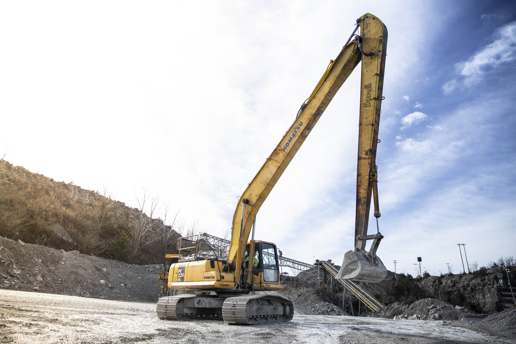 Large excavator operating with a suspended bucket inside a stone quarry