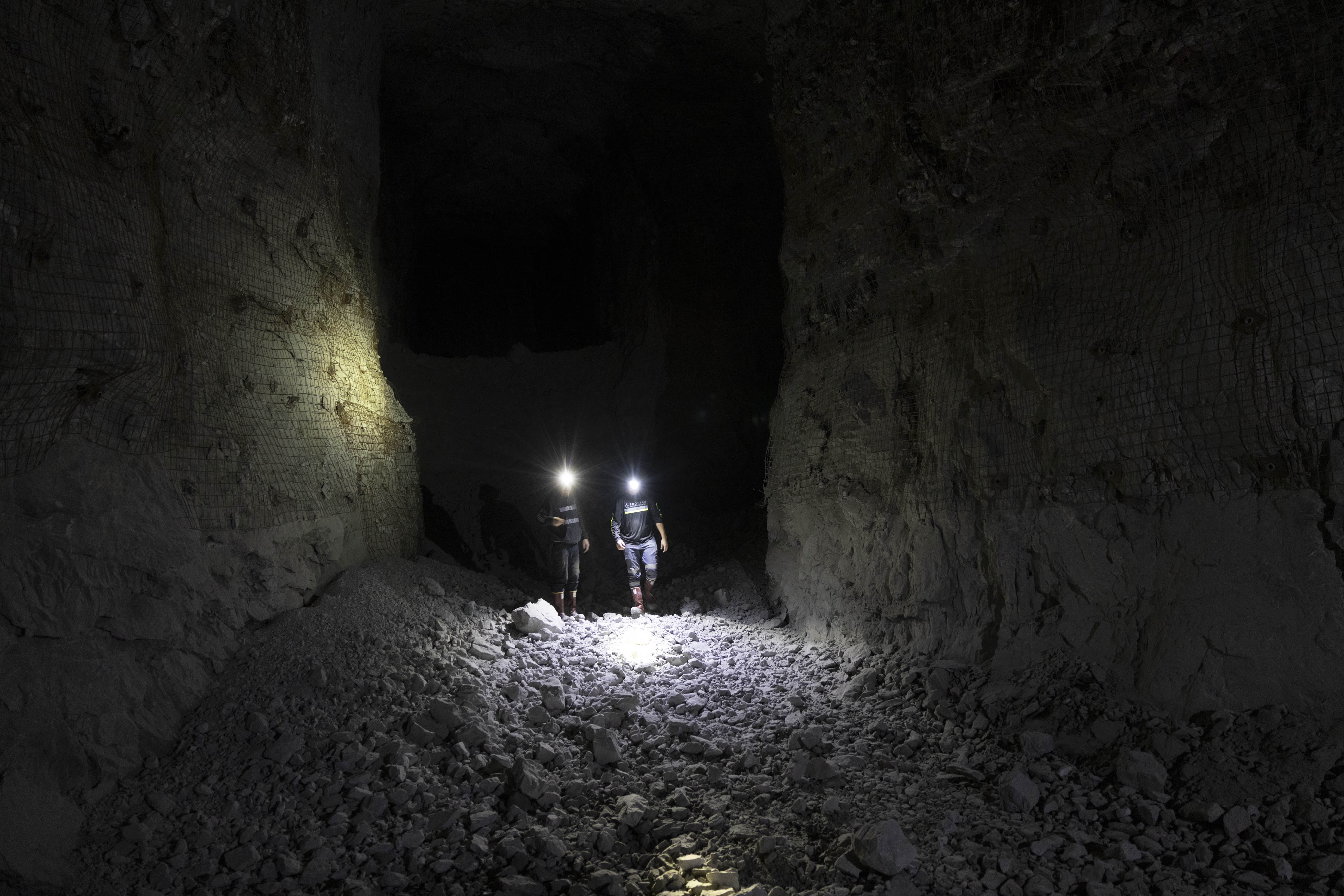 Two underground miners walking through a newly developed hard-rock heading