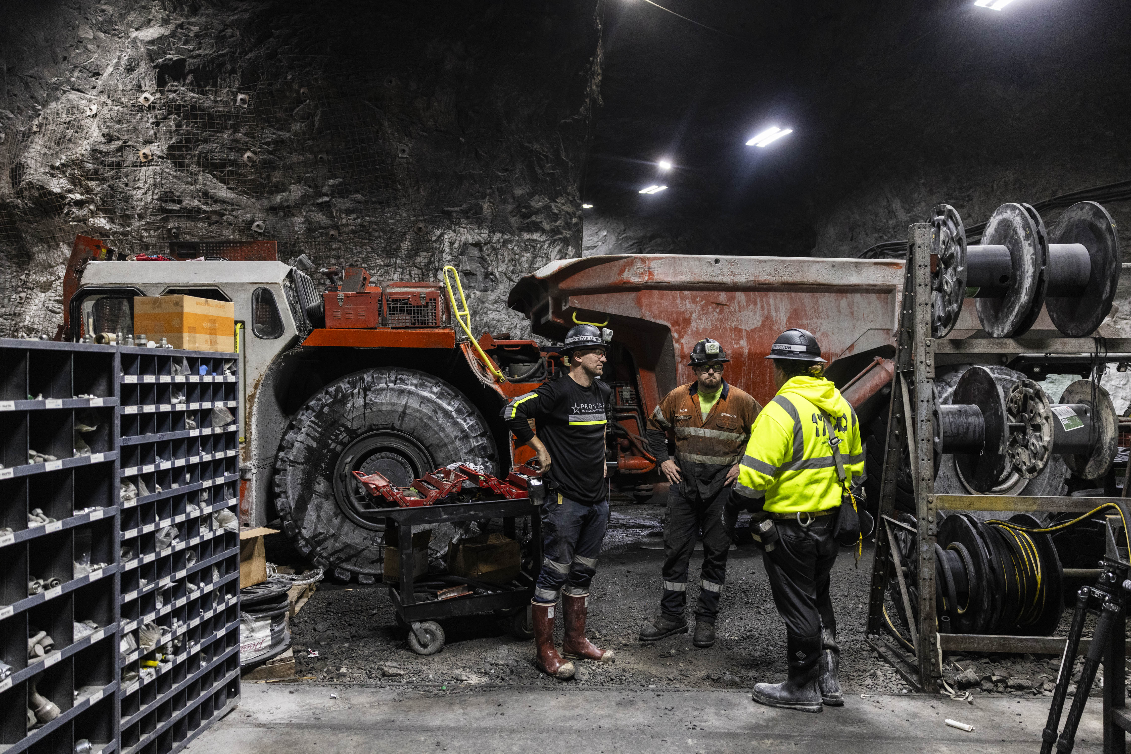 Underground mining crew coordinating equipment maintenance beside a haul truck