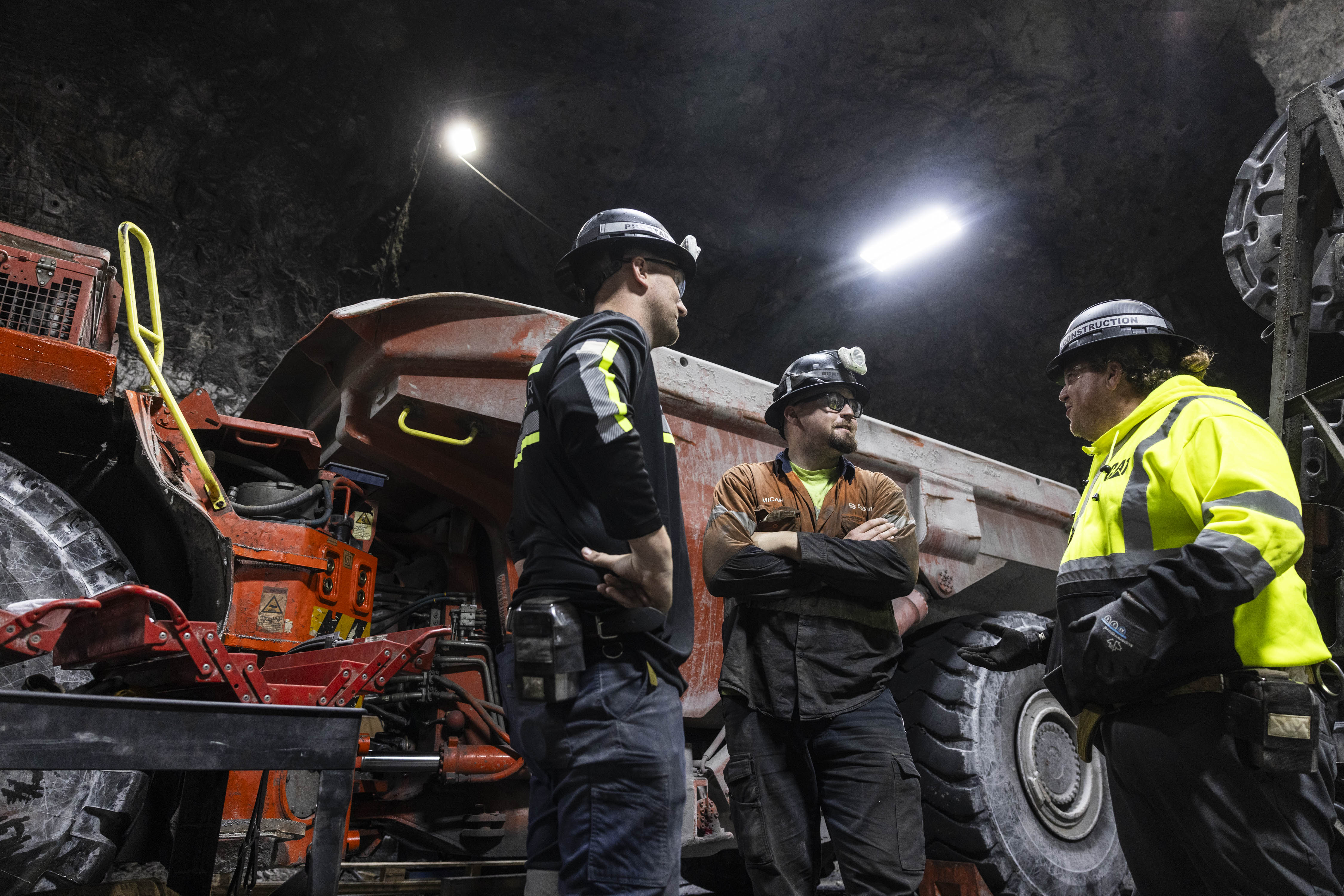 Underground mine development crew coordinating beside heavy equipment