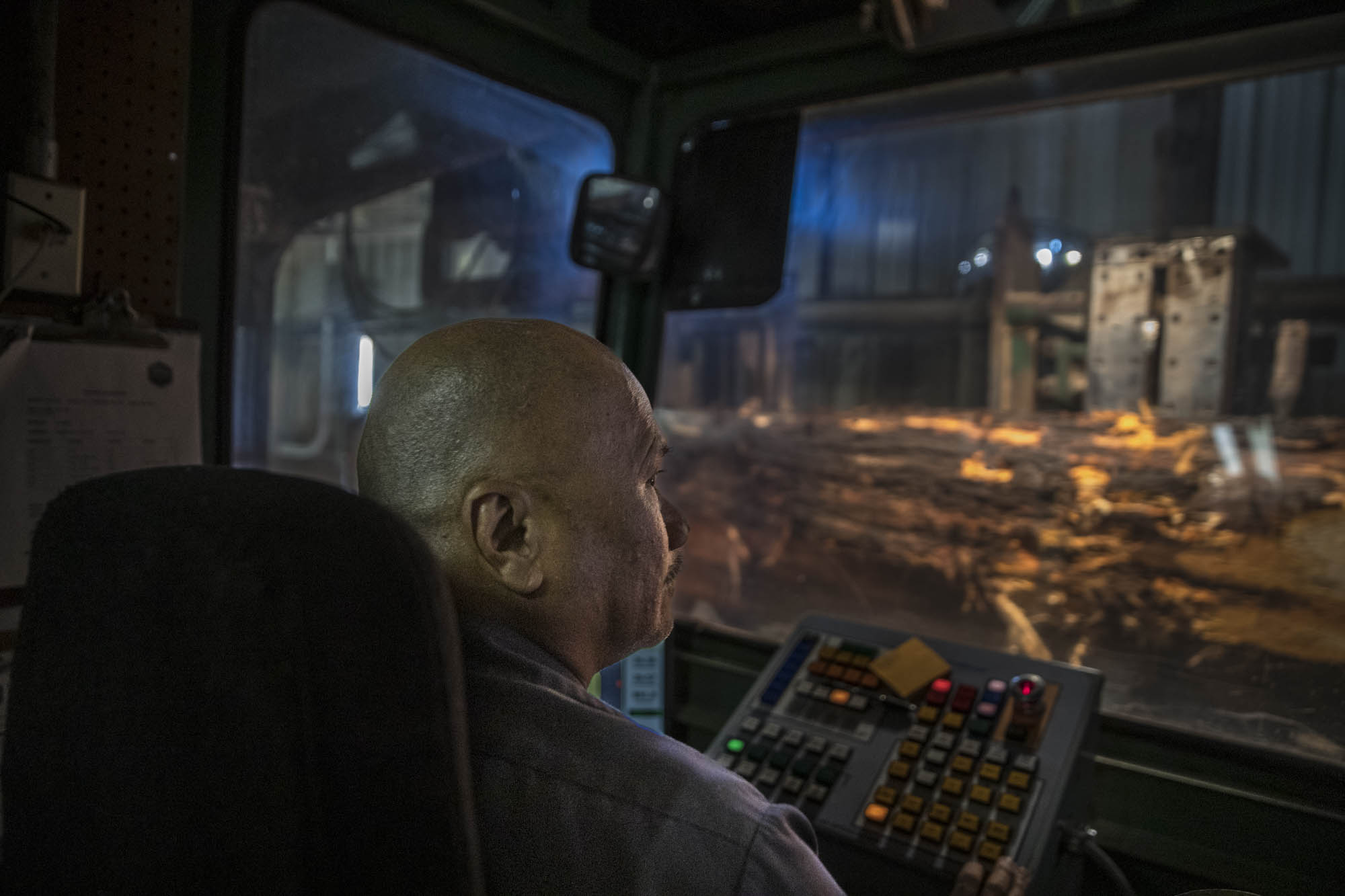Equipment operator running controls from an interior cab at night