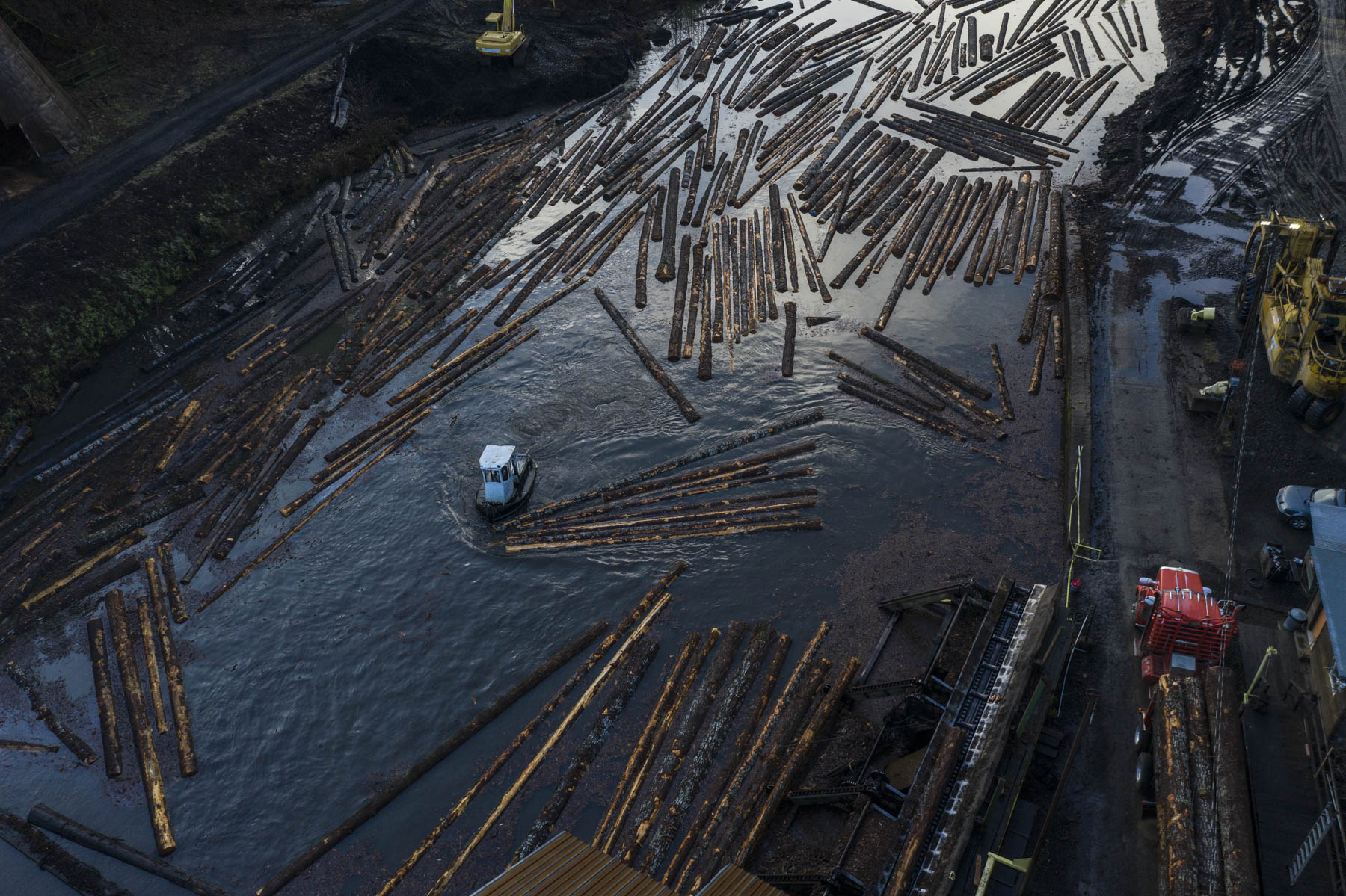Aerial view of floating timber organized across an active mill log pond