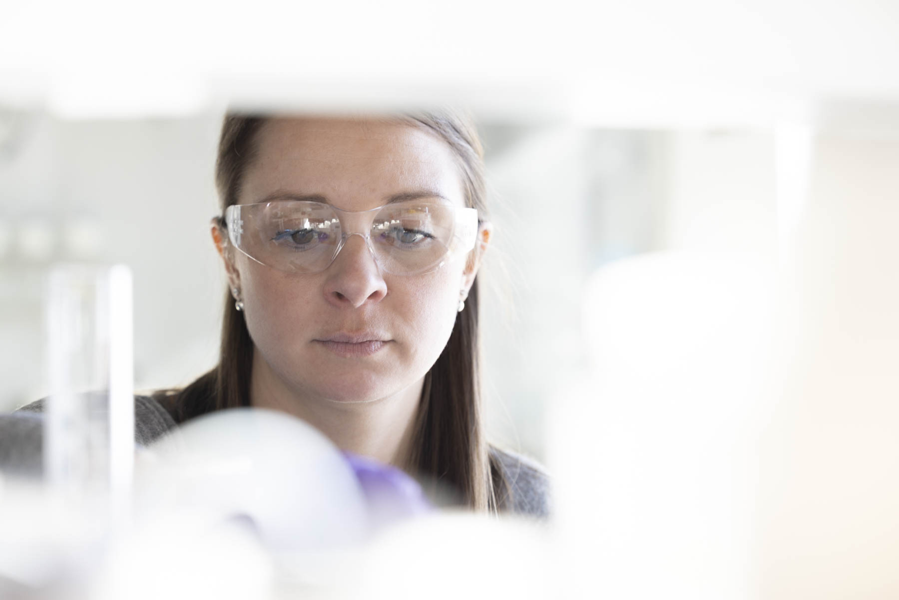 Laboratory researcher inspecting a sample in a bright aerospace test lab