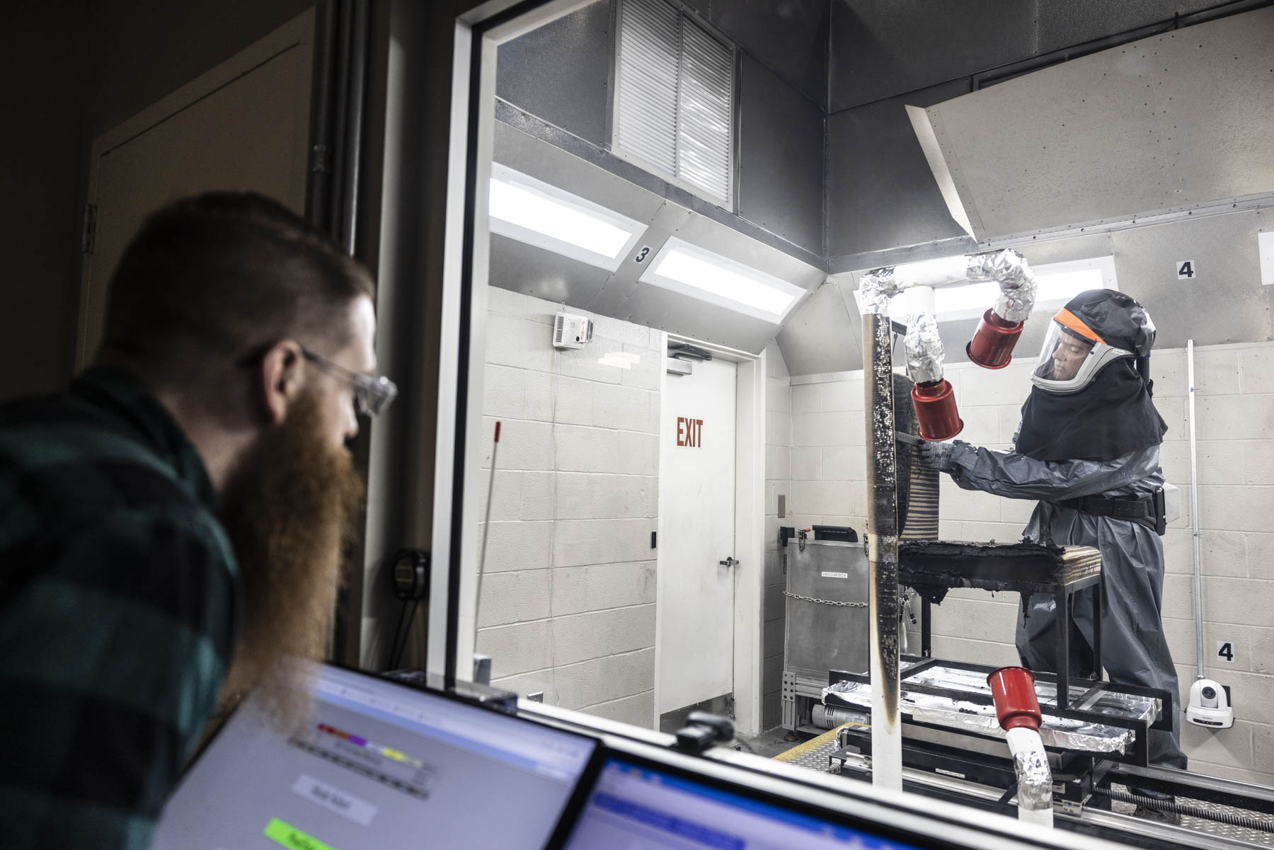 Protected technician conducting aerospace materials flammability testing