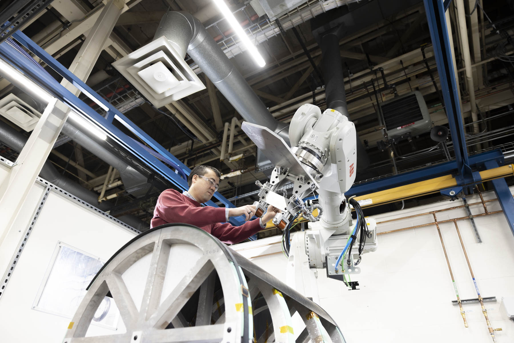 Technicians operating robotic thermal-welding equipment in an advanced manufacturing facility